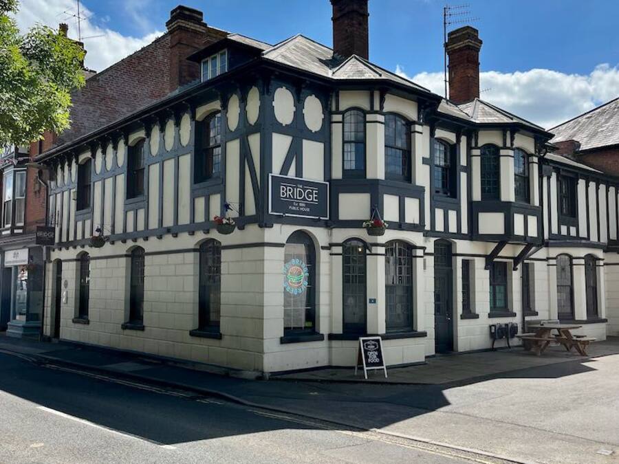 A two-story building with a sign reading 'BRIDGE' on the ground floor, featuring a traditional architectural style with a corner location.