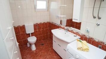 A bathroom with a toilet, sink, and washing machine.