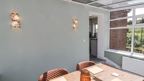 A dining area with a wooden table, two chairs, and a glass ceiling. - Foulsyke Farm Bungalow (Saltburn-by-the-Sea)