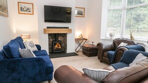 A living room with a fireplace, a television, and a window with blinds. - Cliff House (Saltburn-by-the-Sea)
