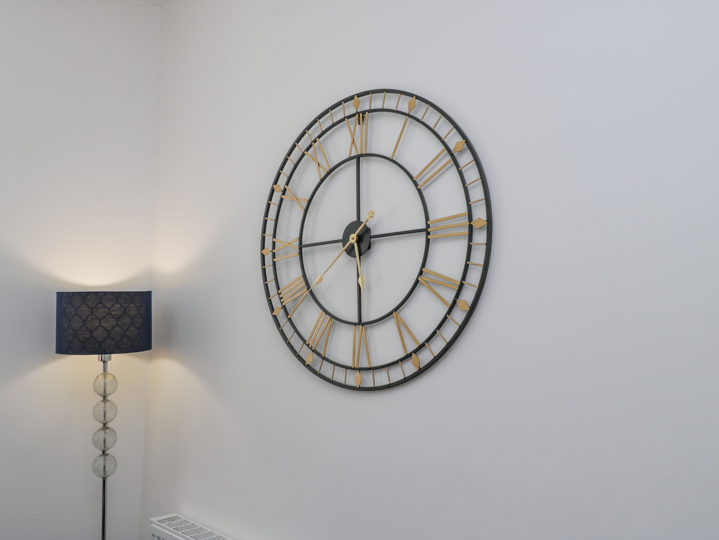 Een wandklok met een minimalistisch design, met een ronde wijzerplaat en Romeinse cijfers.