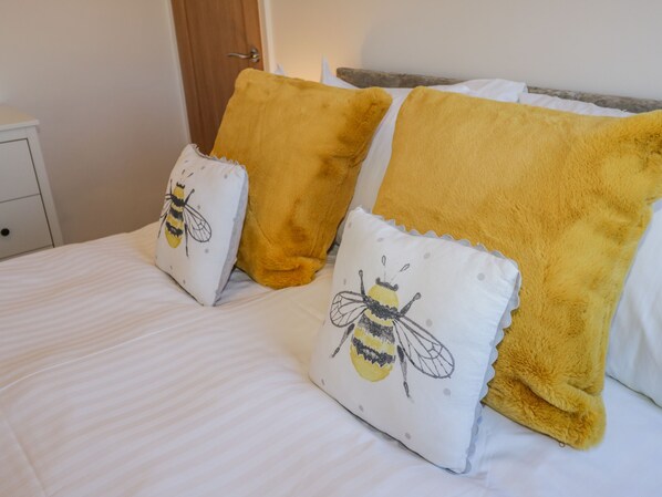 A bed with white bedding and two pillows, one with a bee design and the other plain. - Cliff House (Saltburn-by-the-Sea)