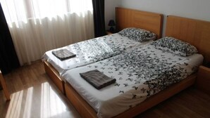 Una cama doble con ropa de cama floral, un cabecero de madera y una mesita de noche con una lámpara.
