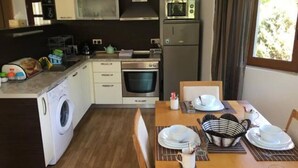 Cocina compacta con microondas, horno y lavadora. Se ha dispuesto una mesa de comedor con platos y cubiertos.