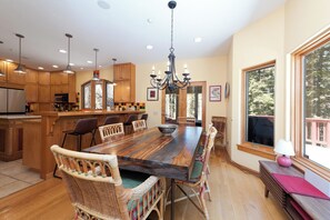 Une salle à manger spacieuse avec une longue table en bois, des chaises en osier et un lustre.