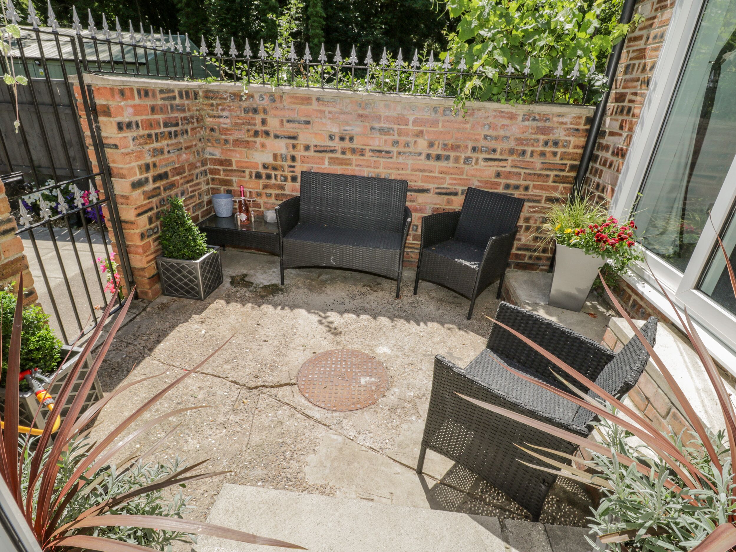 A patio area with two wicker chairs, a small round table, and a brick wall.