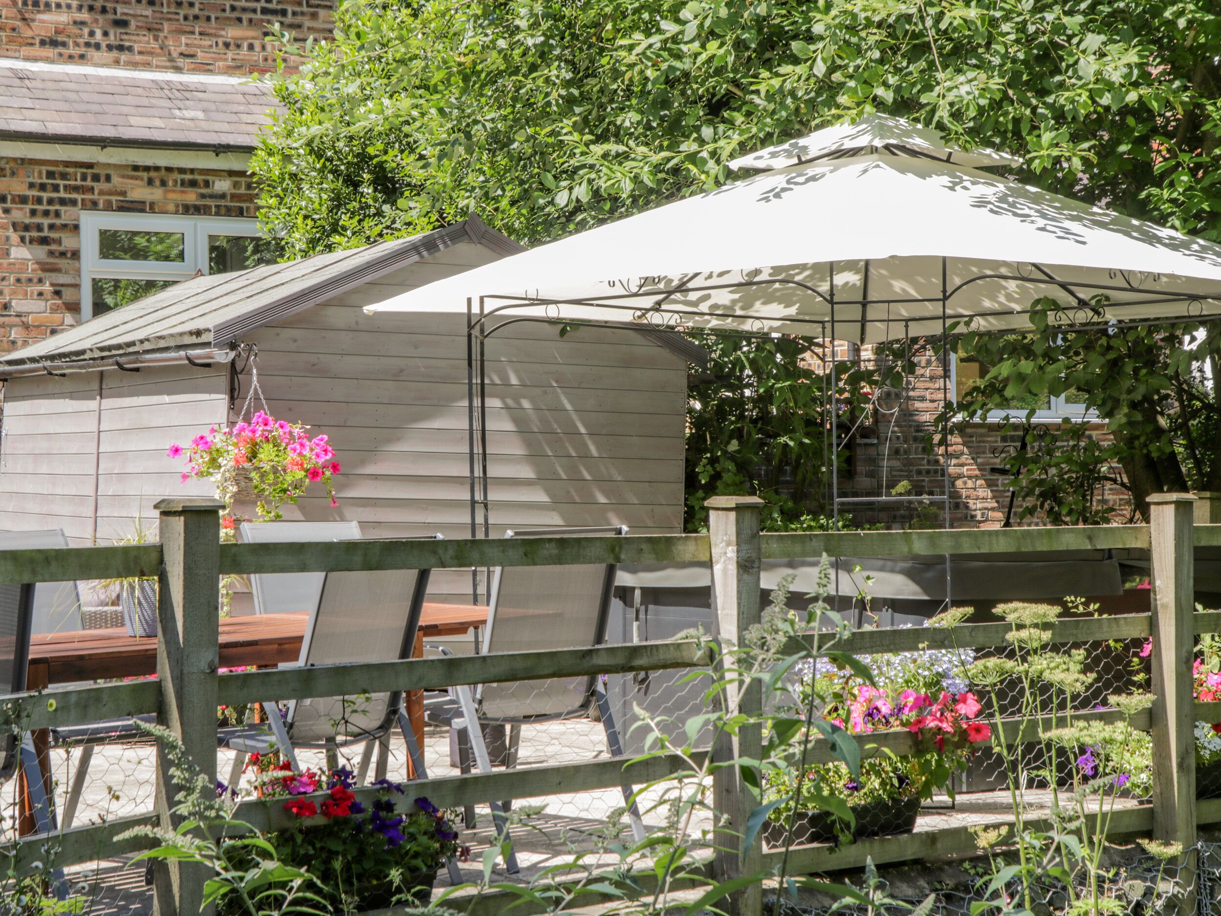 A garden area with a wooden fence, a metal table, and a white umbrella.