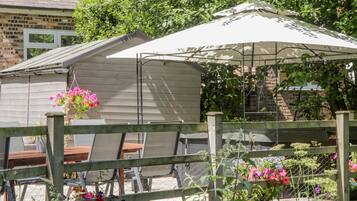 A garden area with a wooden fence, a metal table, and a white umbrella.