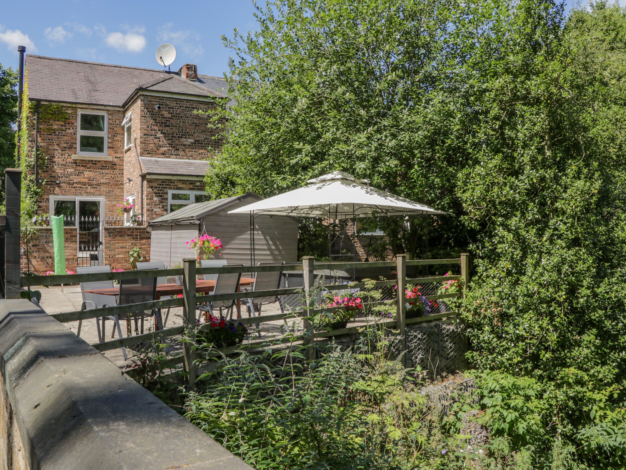 A patio area with outdoor seating, a brick building, and a garden with various plants and flowers.
