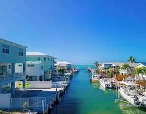 A marina with boats docked, a clear blue sky, and buildings along the water.