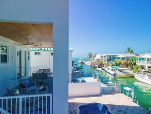 A balcony with a view of a marina, a pool, and a white building with a green roof.
