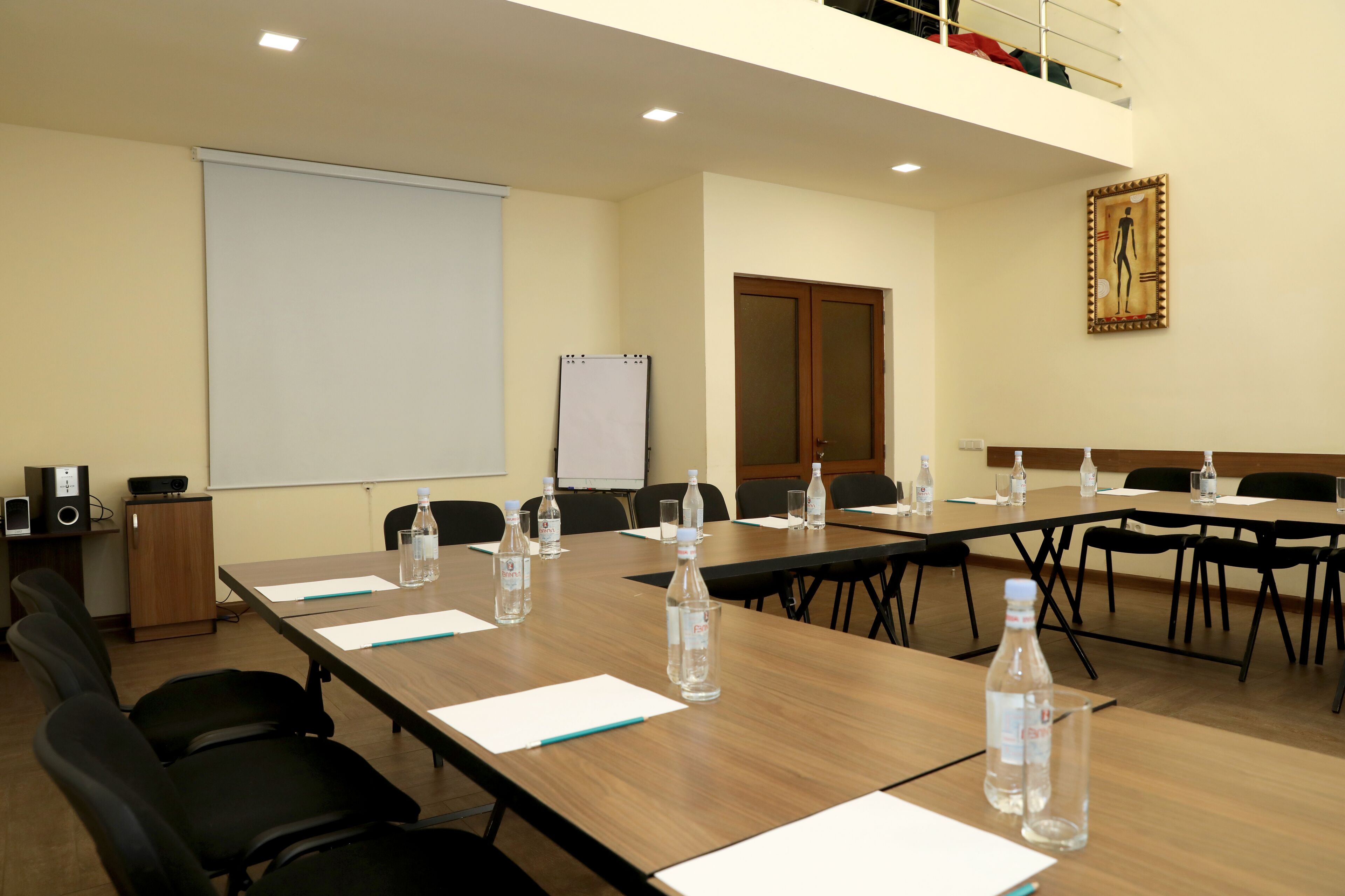 Une salle de conférence équipée d’une longue table, de chaises, d’un projecteur et d’un tableau blanc.
