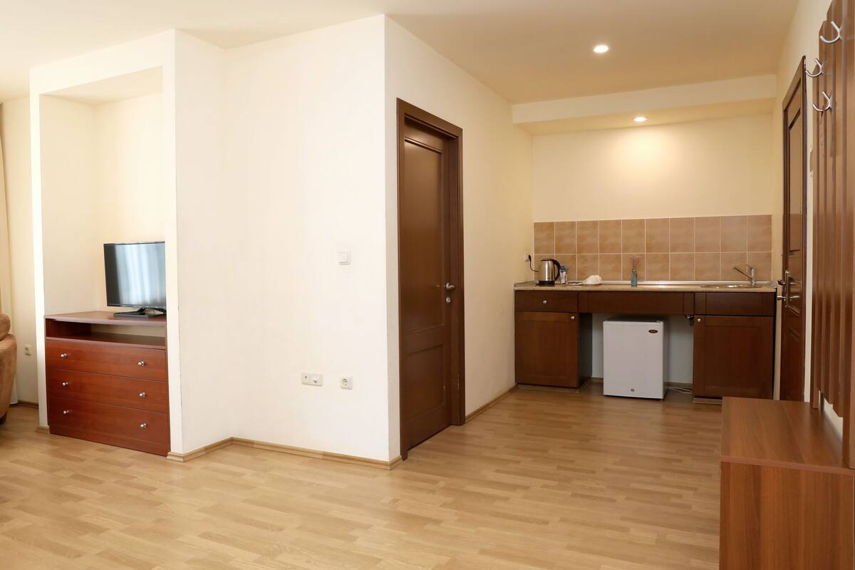 A compact kitchen with wooden cabinets, a built-in dishwasher, and a small refrigerator.