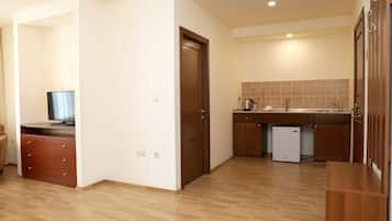 A compact kitchen with wooden cabinets, a built-in dishwasher, and a small refrigerator.