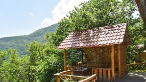 A wooden gazebo with a tiled roof, surrounded by lush greenery and a mountainous backdrop. - Park Resort Aghveran (Arzakan)
