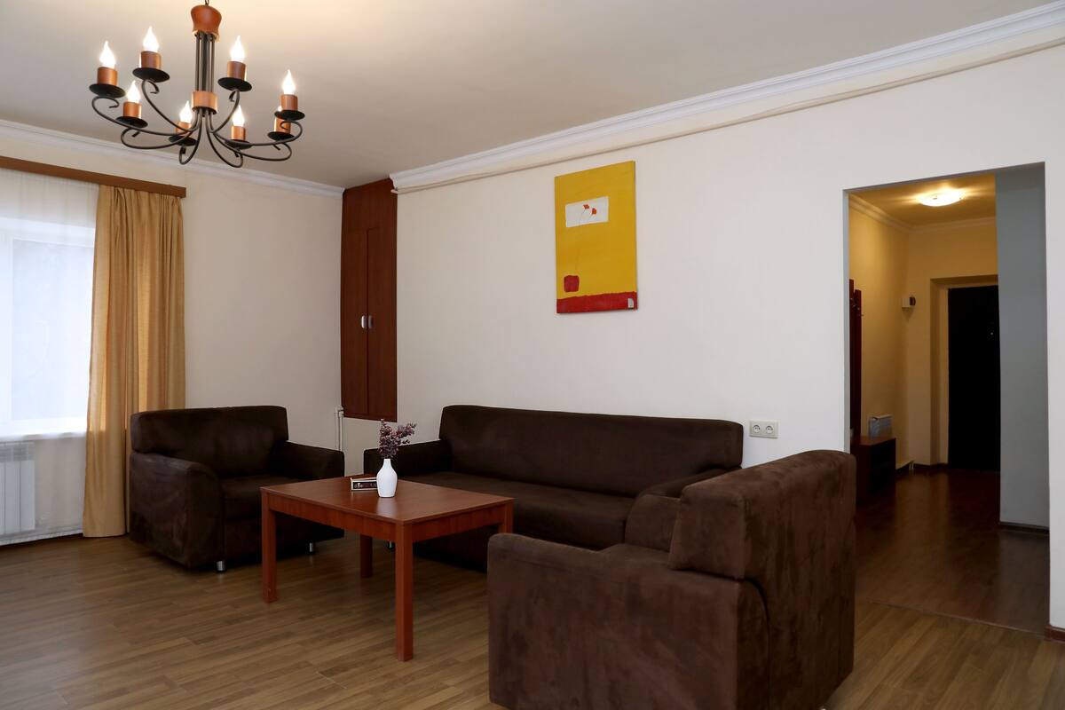 A living room with a brown sofa, a wooden coffee table, and a chandelier.
