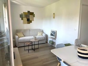 A modern living room with a sofa, a small table, a chair, a framed picture, and a decorative wall piece. - T2 - 4 beds - 50m from the sea (Fréjus)