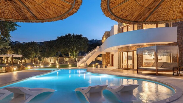 Ein Swimmingpool mit Liegestühlen, einer Treppe und einem Gebäude mit Steinverkleidung.