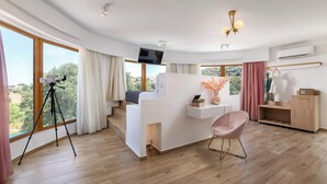 Ein modernes Hotelzimmer mit großem Fenster, Schreibtisch, Stuhl und Fernseher.