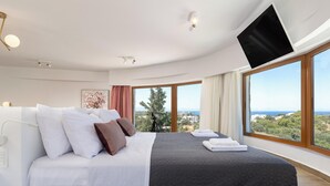 Ein modernes Schlafzimmer mit einem großen Bett, einem Flachbildfernseher und Blick auf die Landschaft.