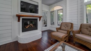 Una sala de estar acogedora con chimenea, muebles de mimbre y vistas al exterior.