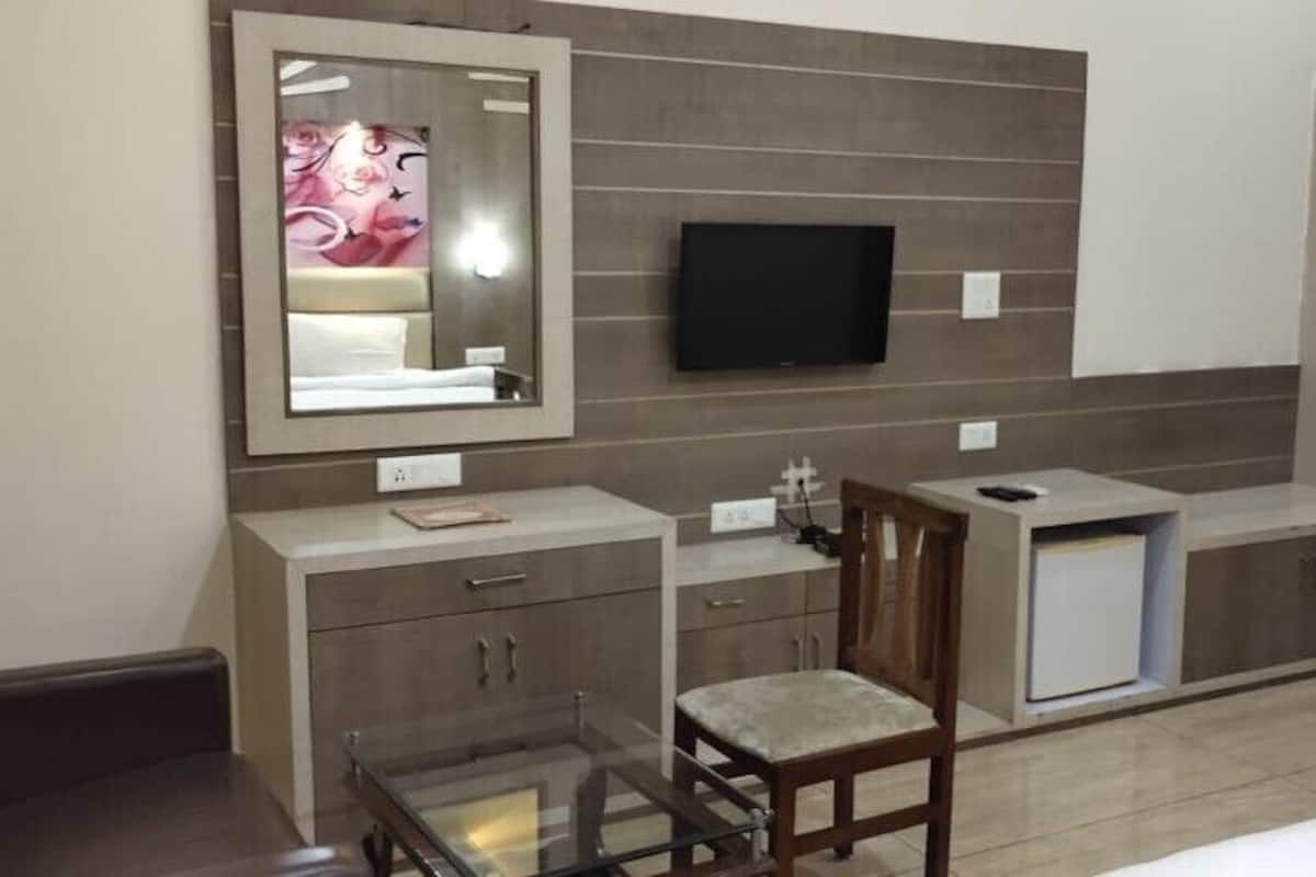 Habitación de hotel con cama, escritorio con silla, televisor montado en la pared y armario.