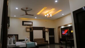 A hotel room with a bed, a sofa, a TV, and a ceiling fan. - Hotel Clarks Inn Express Bharatpur (Bharatpur)