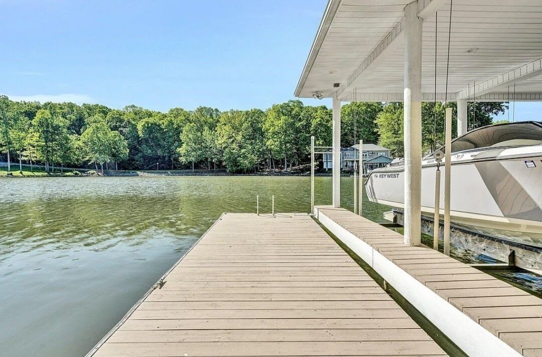 A dock extending into a calm lake with a boat moored nearby.