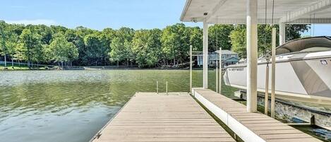 A dock extending into a calm lake with a boat moored nearby.