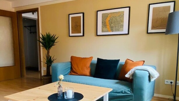 A living room with a light blue sofa, a wooden coffee table, and three framed artworks on the wall. - Cozy apartment at the Engelserker (Pirna)