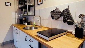 A modern kitchen with a wooden countertop, a built-in oven, a sink, and a black oven mitt hanging on the wall. - Cozy apartment at the Engelserker (Pirna)