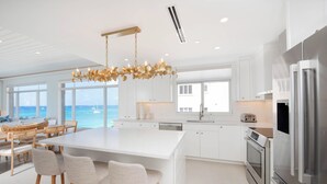 Una cocina moderna con muebles blancos, electrodomésticos de acero inoxidable y una isla grande con taburetes de bar.