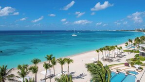 Un resort en la playa con piscina, palmeras y vista al océano.