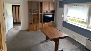Een kamer met een houten kast, een televisie en een raam met uitzicht.
