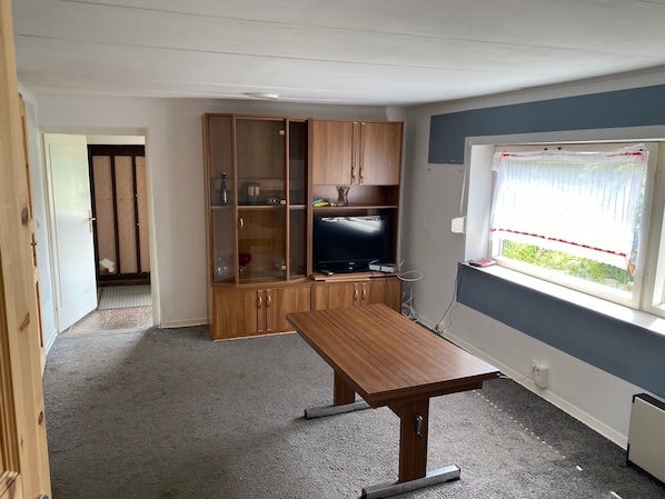 A room with a wooden cabinet, a television, and a window with a view.