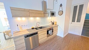 A modern kitchen with wooden cabinets, a stainless steel dishwasher, a microwave, and a built-in oven. - Stone house with jacuzzi 500m from the Ain 3bed 8p (Poncin)