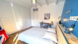 A bedroom with a large bed, a desk, and a chair. There is a wardrobe, a mirror, and a shelf with decorative items. - Stone house with jacuzzi 500m from the Ain 3bed 8p (Poncin)