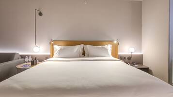 Une chambre d’hôtel avec un grand lit, deux tables de chevet, une petite table, une lampe et un luminaire fixé au mur.