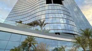A modern high-rise building with a curved glass facade and a central entrance.