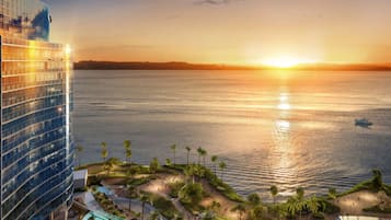 A high-rise hotel overlooking a body of water at sunset.