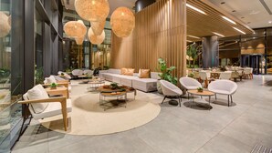 A modern lobby with a seating area, a reception desk, and a large plant.