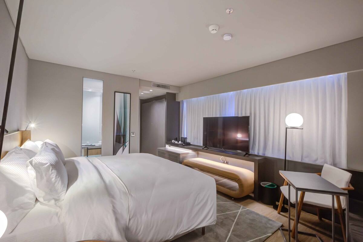 Une chambre d’hôtel moderne équipée d’un grand lit, d’une télévision, d’un bureau et d’un coin salon.
