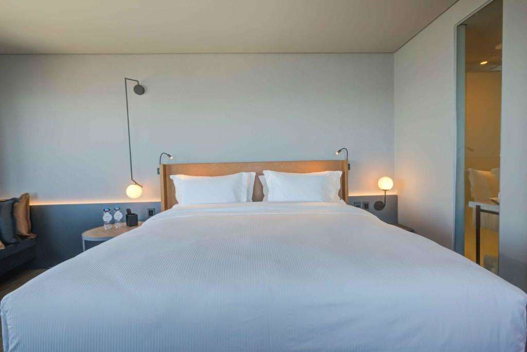 Una habitación de hotel moderna con una cama grande, mesitas de noche y lámparas fijadas a la pared.