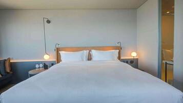 Una habitación de hotel moderna con una cama grande, mesitas de noche y lámparas fijadas a la pared.