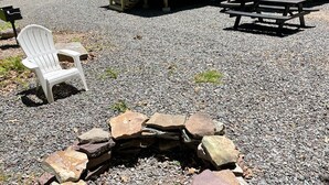 A wooden cabin with a porch, a stone fire pit, and a picnic table. - Ricketts Glen Fern View Cabin (Benton)