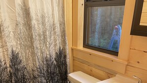 A bathroom with a toilet, sink, and window. - Ricketts Glen Fern View Cabin (Benton)
