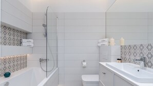 A modern bathroom with a bathtub, toilet, and sink. - EXCLUSIVE Aparthotel KRK Lubicz C4 with Garden (Kraków)
