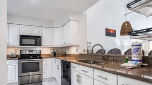 Una cocina moderna con armarios blancos, electrodomésticos de acero inoxidable y encimera de granito.