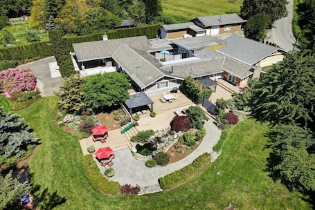 An aerial view of a modern two-story house with a spacious backyard, including a patio, a swimming pool, and a well-maintained garden.