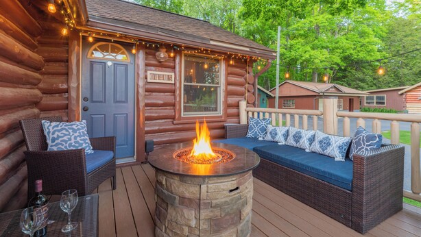 A log cabin with a fire pit, outdoor seating, and a deck.